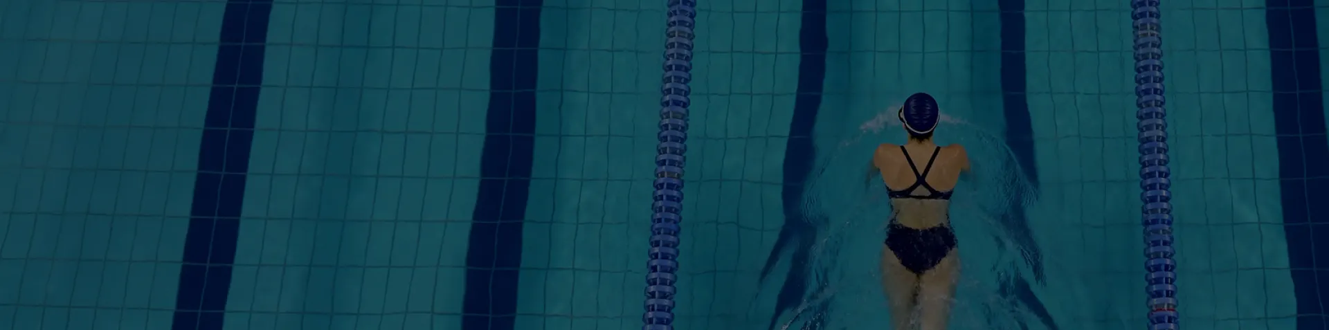 Mulher nadando na piscina com traje de natação.